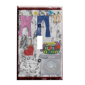 May include: A light switch cover with a laundry room theme. The cover features a distressed white background with a red heart, a clothesline with clothes hanging on it, a basket of laundry, and a washing machine. The text "Laundry Room" is written in a vintage font with the words "Wash, Dry, Fold, 5+ Repeat" underneath.