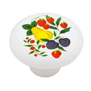 May include: A white ceramic knob with a colorful fruit design. The design features a yellow pear, red strawberries, and purple plums with green leaves.