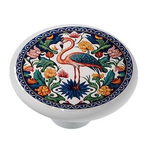 May include: A white ceramic knob with a colorful design featuring a pink flamingo standing in a blue and green floral pattern.