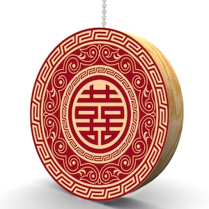 May include: A red and gold circular ornament with a traditional Chinese double happiness symbol in the center. The ornament is surrounded by a decorative border.