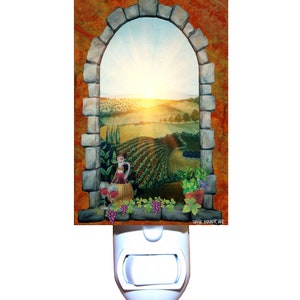 May include: A decorative night light featuring a painted scene of a vineyard viewed through a stone archway. The image includes a bottle of wine, glasses, and grapes. The background shows a sunset over rolling hills. The night light has a white plastic base.