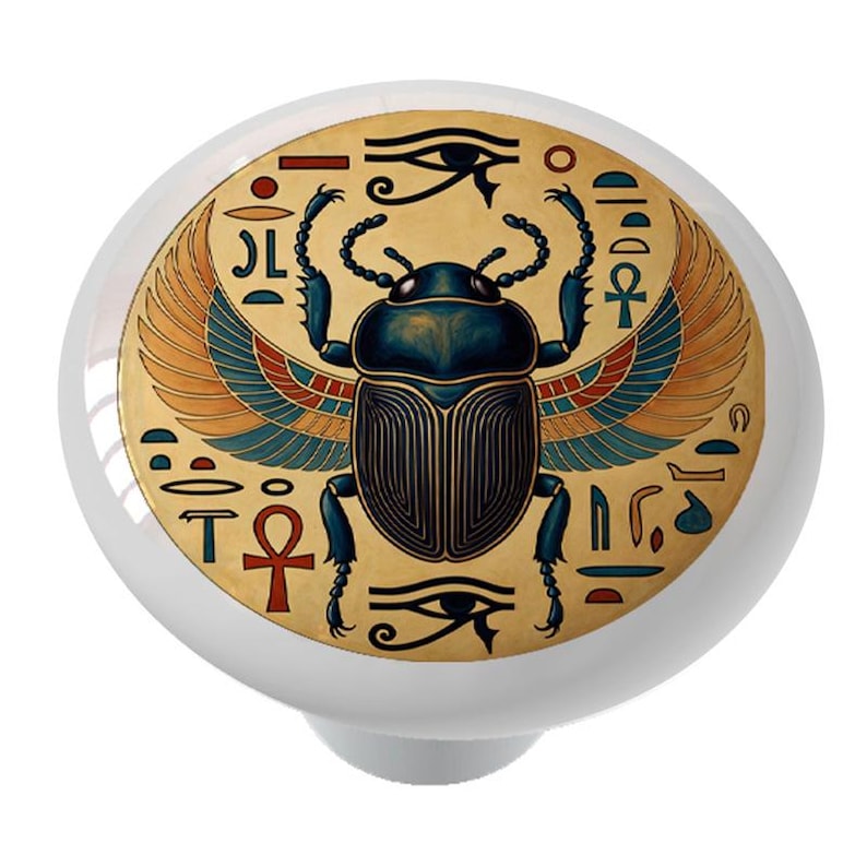 Puede incluir: Pomo de armario de cer&aacute;mica blanca con un dise&ntilde;o de escarabajo egipcio. El escarabajo est&aacute; representado con detalles en azul, dorado y rojo, rodeado de jerogl&iacute;ficos y el Ojo de Horus. Un acento decorativo para muebles.
