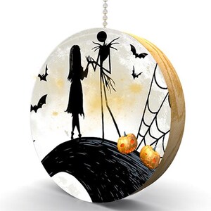 May include: A black and white silhouette of Jack Skellington and Sally from the Nightmare Before Christmas movie on a white background with a moon and bats. The image is on a round wooden pull chain for a light fixture.