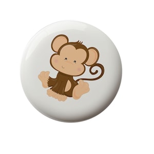 May include: A brown and white cartoon monkey with a curled tail. The monkey is sitting with its legs crossed and has a happy expression on its face.