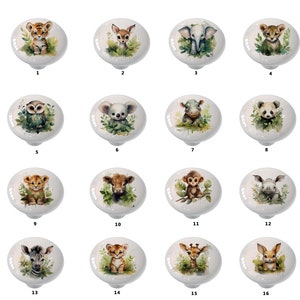 May include: A collection of sixteen white ceramic cabinet knobs, each featuring a watercolor illustration of a different baby animal. The animals include a tiger, deer, elephant, leopard, owl, koala, hippo, panda, lion, calf, monkey, rhino, zebra, giraffe, and bunny.