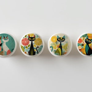 May include: Four white cabinet knobs with colorful cat designs. Each knob features a different cat illustration with citrus fruit and botanical elements. The cats are black, white, and teal, with orange and yellow accents.