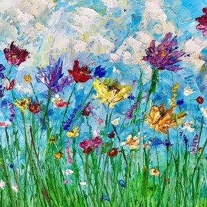 May include: An impressionistic painting of a wildflower meadow. The artwork features a vibrant array of colorful flowers in shades of red, yellow, purple, and white, set against a bright blue sky with fluffy white clouds. Green grass fills the foreground.