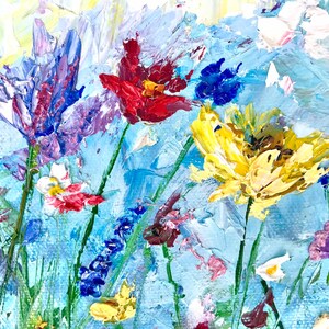 May include: An impressionistic painting of a wildflower meadow. The artwork features a variety of colorful flowers, including red, yellow, purple, and white blooms, set against a light blue background. The thick brushstrokes create a textured, vibrant effect, evoking a sense of nature and beauty.