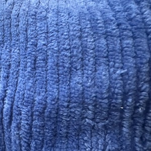 May include: Close-up of a blue fuzzy fabric with a ribbed texture. The fabric is soft and plush.