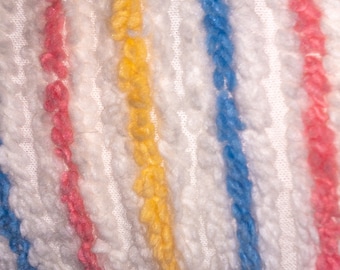 Puede incluir: Tela blanca con rayas de hilo rosa, amarillo y azul. El hilo está tejido en la tela, creando un aspecto texturizado.
