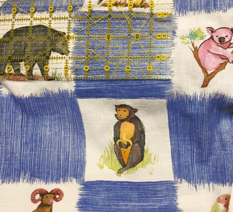 Puede incluir: Una tela blanca con un patr&oacute;n de rayas azules y blancas. La tela presenta una variedad de ilustraciones de animales, incluyendo un oso, un mono, un koala y un carnero. La tela es perfecta para proyectos de manualidades, como acolchar, coser y scrapbooking.