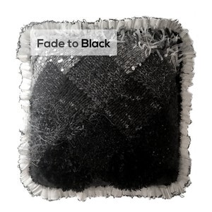 Puede incluir: Una almohada cuadrada en blanco y negro con un borde deshilachado y un ribete de encaje blanco. La almohada tiene una superficie texturizada y las palabras "Fade to Black" están impresas en la parte delantera.