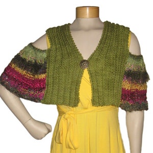 Puede incluir: Una estola de punto verde con cuello en V y un botón decorativo. La estola tiene mangas a rayas de colores con un hilo multicolor.