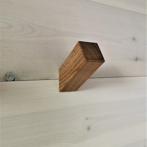Könnte beinhalten: Ein rechteckiger Wandhaken aus Holz mit einer natürlichen braunen Oberfläche.