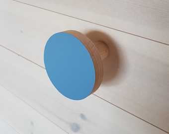 May include: A light blue round wooden knob with a natural wood base. The knob is mounted on a white wooden wall.