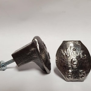 May include: Two silver-colored metal cabinet knobs with a square base and a rounded, textured front. One knob has a bolt and washer attached. The other knob has the letters "WA" and numbers "95" embossed on the front.