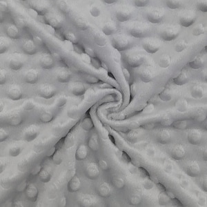 May include: A close-up of a soft, grey, textured fabric with a subtle pattern of raised dots. The fabric is wrinkled and folded, showing its texture.