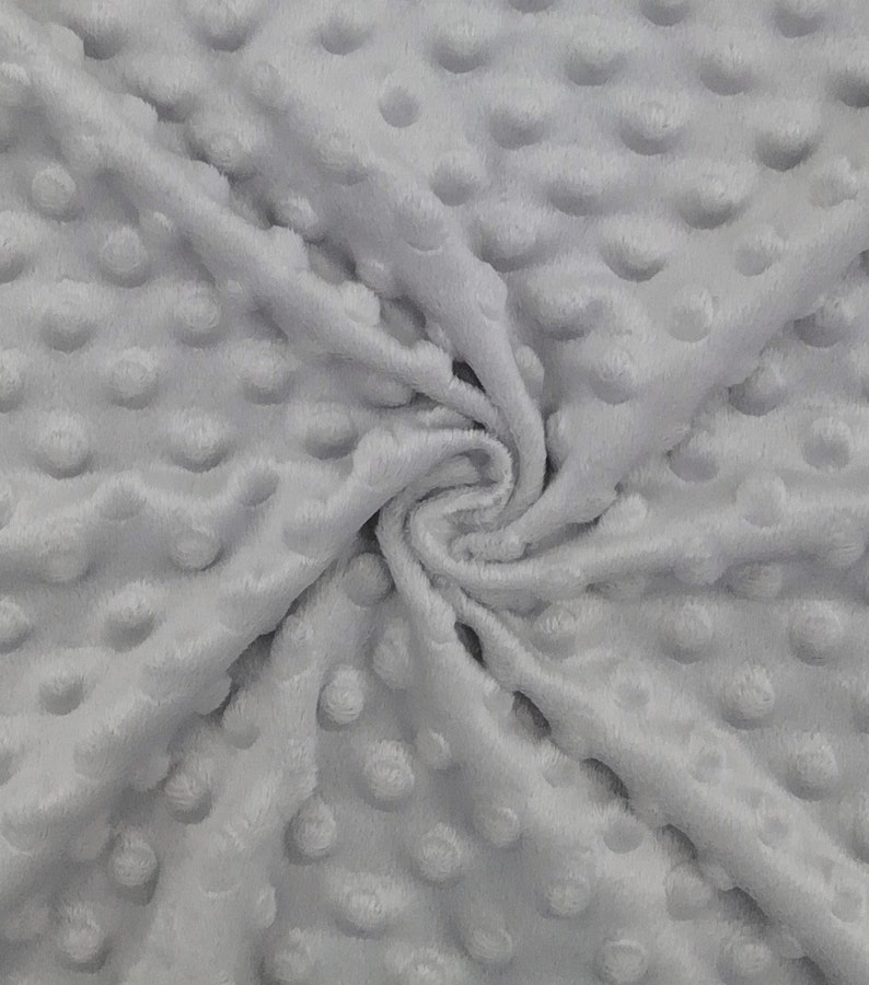 May include: A close-up of a soft, grey, textured fabric with a subtle pattern of raised dots. The fabric is wrinkled and folded, showing its texture.