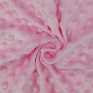 May include: Pink fabric with a textured, raised dot pattern. The fabric is soft and plush.