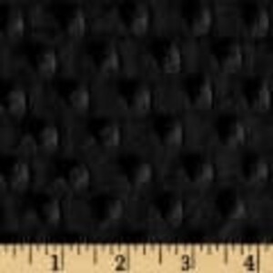 May include: Black fabric with a textured, raised dot pattern. The pattern is evenly spaced across the material. A ruler is shown along the bottom, with measurements in inches.
