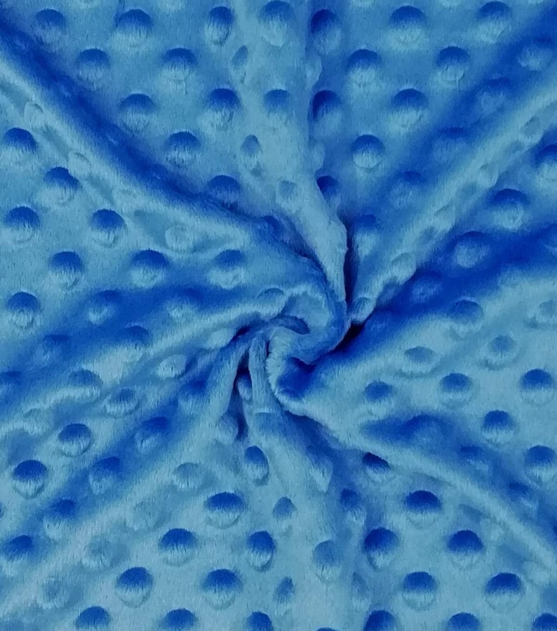 K&ouml;nnte beinhalten: Nahaufnahme eines weichen, blauen Stoffes mit einem strukturierten, gepunkteten Muster. Der Stoff ist zerknittert und gefaltet, wodurch die Textur des Materials sichtbar wird.