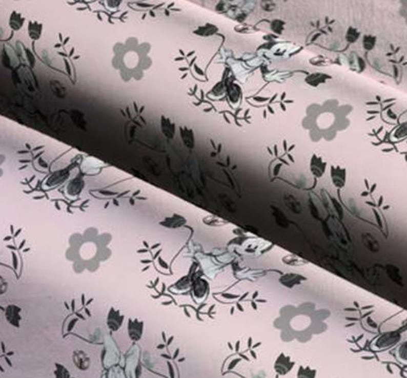 May include: Pink fabric with a repeating pattern of black and white cartoon mice, flowers, and leaves.