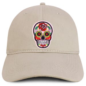 Peut inclure: Casquette de baseball beige or sable avec un écusson de tête de mort mexicaine colorée. L'écusson comprend une rose rouge, des détails jaunes et un bord rose. Visière incurvée et sangle réglable.