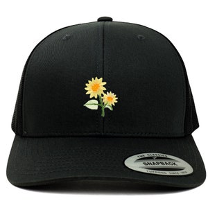 May include: Black trucker hat with a yellow embroidered sunflower design. The hat has a mesh back and a snap closure. The hat is labeled "The Classics" and "Snapback" with the Yupoong logo.
