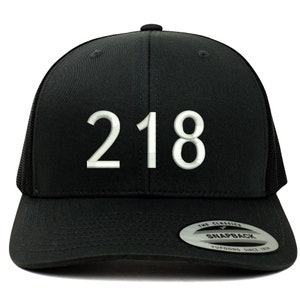 Könnte beinhalten: Schwarze Trucker-Kappe mit einer weißen gestickten Nummer "218" auf der Vorderseite. Die Kappe hat ein schwarzes Netzrücken und einen schwarzen Druckknopfverschluss.