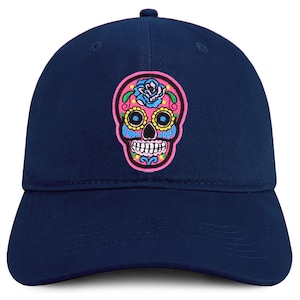 May include: A navy blue baseball cap featuring a colorful sugar skull design. The skull has pink, blue, yellow, and green accents, with a floral design on top. The cap is a classic six-panel style.