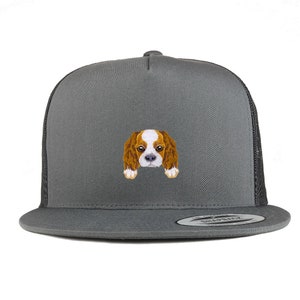 Puede incluir: Una gorra de camionero gris con una malla negra en la parte posterior. La gorra presenta una imagen bordada de un cachorro Cavalier King Charles Spaniel.