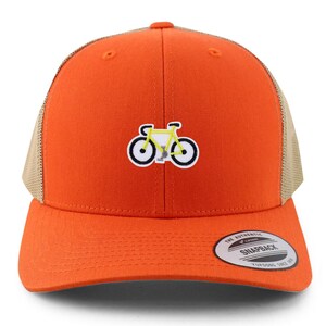 May include: Orange trucker cap with a yellow bicycle graphic. The cap has a mesh back and a curved peak. The front panel displays a small embroidered bicycle design with black and white details. It has a snapback closure and a Yupoong Snapback tag.