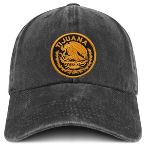 May include: A dark gray baseball cap with a curved brim. The cap features a circular patch with the word "TIJUANA" in a ring around a gold emblem of an eagle. The cap is made of a worn, textured fabric.