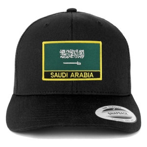 Puede incluir: Gorra de camionero negra con un parche de la bandera de Arabia Saudita verde, blanco y negro. El parche tiene costuras amarillas y las palabras "Arabia Saudita" están impresas debajo de la bandera. La gorra tiene una parte trasera de malla negra y un cierre de presión negro.