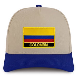 May include: A beige and blue baseball cap with an embroidered patch of the Colombian flag and the word "COLOMBIA" in yellow lettering.