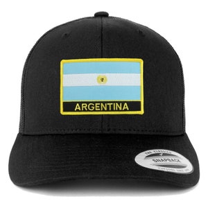 May include: Black trucker hat with a yellow and black patch featuring the flag of Argentina and the word "ARGENTINA". The hat has a black mesh back and a black snap closure. The hat also has a "The Classics" sticker on the back.