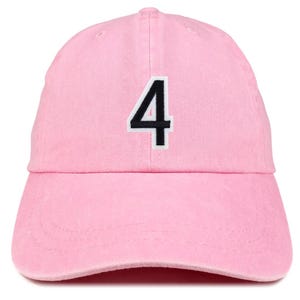 May include: A light pink baseball cap with a curved brim. The number "4" is embroidered on the front in black with a white border. The cap is made of a soft, textured fabric.