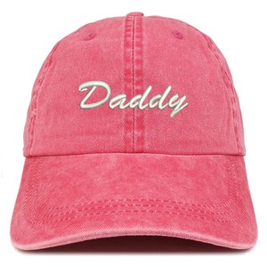 May include: A red baseball cap with the word "Daddy" embroidered in white script across the front. The cap has a curved brim and an adjustable strap at the back. The fabric has a slightly faded, vintage look.