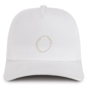 May include: White baseball cap with a gold circle design on the front. The circle is made of small gold dots.