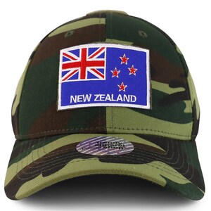 Könnte beinhalten: Eine Baseballkappe in Tarnmuster mit einem neuseeländischen Flaggen-Patch. Der Patch ist blau mit roten Sternen und einem rot-weiß-blauen Union Jack oben links. Der Text "NEW ZEALAND" ist in Weiß unter der Flagge aufgedruckt.