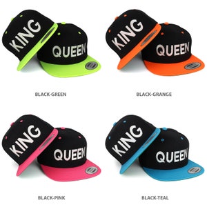 Puede incluir: Cuatro pares de gorras de béisbol negras con las palabras "KING" y "QUEEN" en ellas. Las gorras están en diferentes combinaciones de colores: negro y verde, negro y naranja, negro y rosa y negro y azul verdoso.