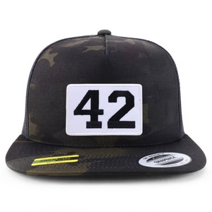 Puede incluir: Una gorra de camionero de camuflaje negro y verde con un parche blanco que dice "42" en negro.