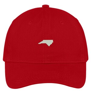 Puede incluir: Gorra de b&eacute;isbol roja con un contorno bordado blanco del estado de Carolina del Norte.