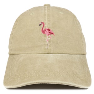 May include: A tan baseball cap with a pink flamingo embroidered on the front. The flamingo is depicted in a standing pose with its head turned to the side. The cap has a curved brim and an adjustable strap.