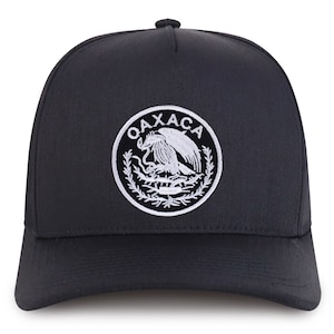 May include: A black baseball cap with a white embroidered emblem featuring a stylized eagle and the text "OAXACA".