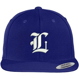 May include: A royal blue baseball cap with a white embroidered letter "L" in an old English font.