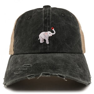 Könnte beinhalten: Eine schwarze und braune, abgenutzte Trucker-Kappe mit einem kleinen gestickten Elefanten, der einen roten Ball hält.