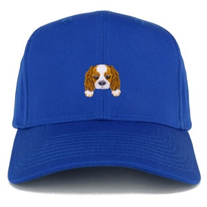 Op de afbeelding: Een koninklijk blauwe baseballpet met een geborduurd beeld van een Cavalier King Charles Spaniel hond.