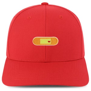 Könnte beinhalten: Rote Baseballkappe mit einem gestickten Pflaster in Gelb und Orange mit einem roten Herzen in der Mitte.