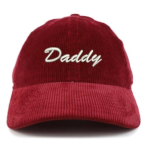 May include: A burgundy corduroy baseball cap with the word "Daddy" embroidered in white script across the front. The cap has a curved brim and a structured crown, suitable for casual wear.
